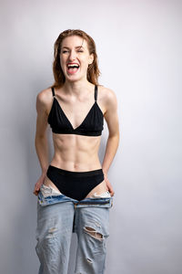 Portrait of young woman standing against white background