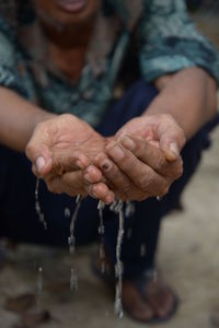 Low section of man holding water in cupped hands