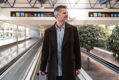 Man looking away while standing on escalator