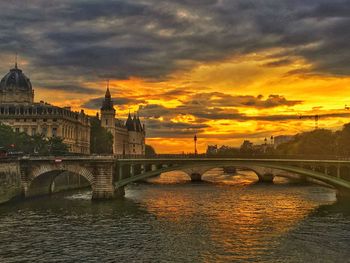 Bridge over river against cloudy sky during sunset