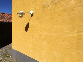 Electric light on yellow wall during sunny day