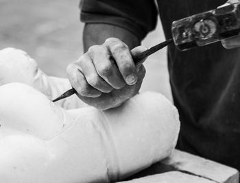 Cropped hand of sculptor carving shape