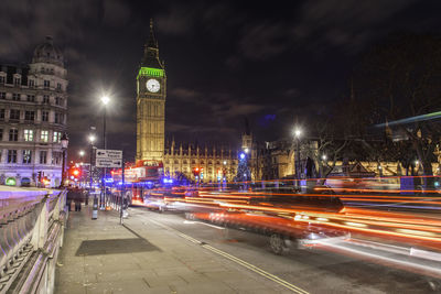 Light trails by big ben in city at night