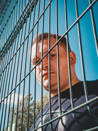 Low angle portrait of man seen through fence