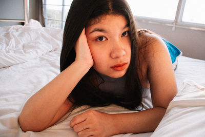 Portrait of young woman lying on bed at home