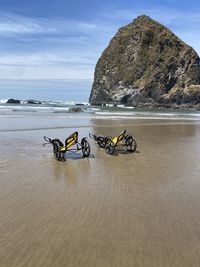 Deck chairs on rock by sea against sky