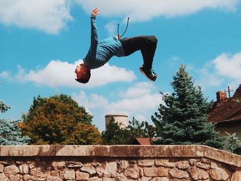 Low angle view of man jumping against sky