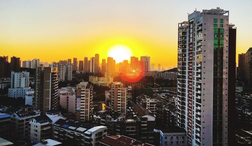 Modern buildings in city against sky during sunset