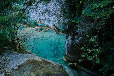 Man standing on rock by river in forest