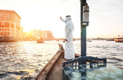 Side view of man standing in boat on river at sunset