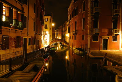 Illuminated street amidst buildings in city at night