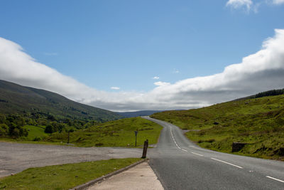 Road leading towards mountains against sky