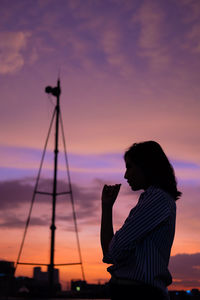 Silhouette woman photographing against sky during sunset