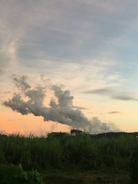 Smoke emitting from chimney on field against sky