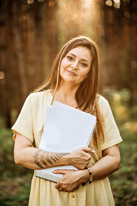 Outdoor mockup with woman holding empty paper document sheet with copy space.
