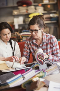 Mature owner showing fabric swatches to customer at store