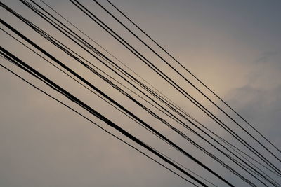 Low angle view of power cables against sky