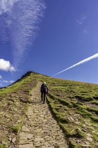 Rear view of man walking on trail against sky