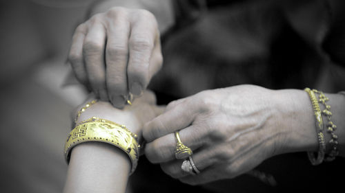 Cropped image of woman putting bracelet around brides hand