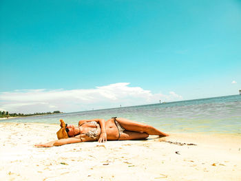 A young lady is laying on the beach