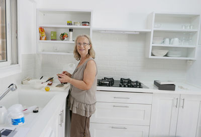 Happy woman washing crockery in kitchen