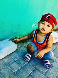 Cute boy looking away while sitting on wall