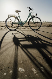 Bicycle with long shadow at fangar beach against clear sky, ebro delta, spain