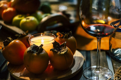 Close-up of wine in glass by fruits and illuminated candle on table