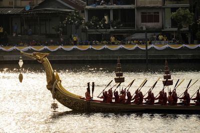 Group of people on boat in river against buildings