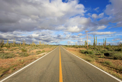 Road passing through landscape against cloudy sky