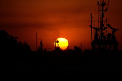 Silhouette cranes against sky during sunset