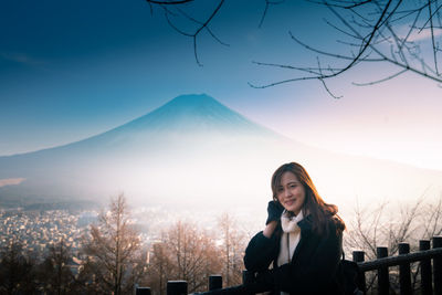 Portrait of smiling woman against mountains during winter