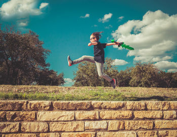 Side view of playful boy jumping over retaining wall