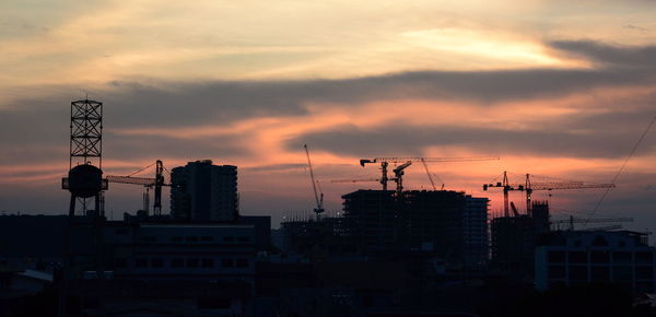 Silhouette buildings against sky at sunset