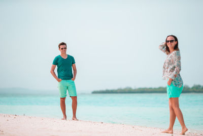 Full length of young man standing on beach against clear sky