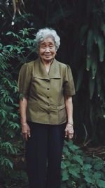 Portrait of smiling woman standing against plants