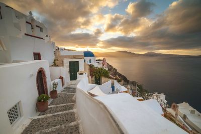 Church at santorini by sea against cloudy sky