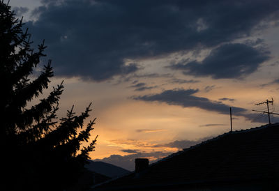 Silhouette houses against sky during sunset