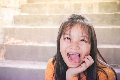 Portrait of girl sticking out tongue while sitting on steps