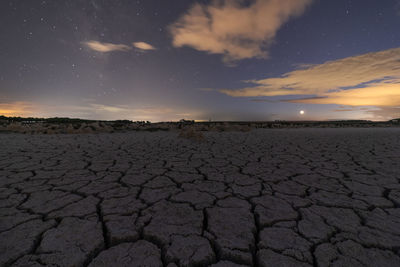 Surface level of barren land against sky