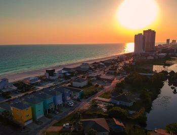 High angle view of buildings by sea against sky during sunset