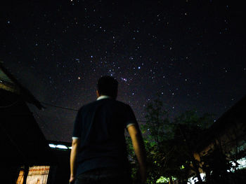 Rear view of man standing against sky at night