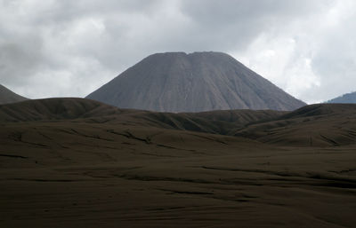 Scenic view of desert against cloudy sky