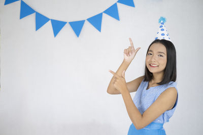 Portrait of smiling young woman standing against wall