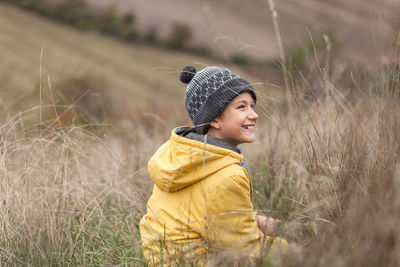 Happy little boy relaxing during autumn day in tall grass on a hill.
