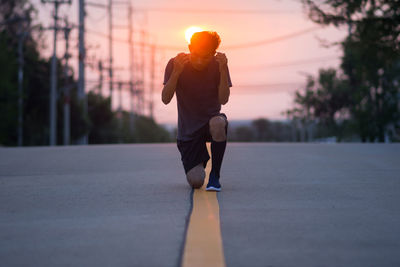 Man running on road at sunset