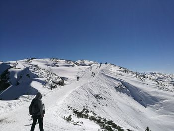 Rear view of man skiing on snowcapped mountain against clear sky