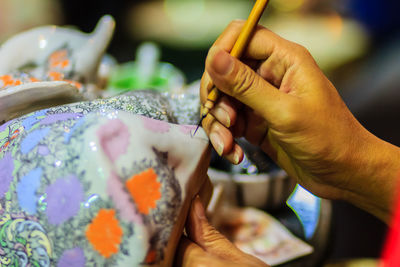 Cropped image of artist painting on ceramics