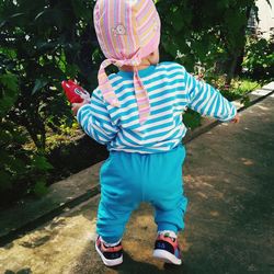 Rear view of boy standing with umbrella