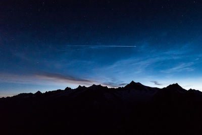 Scenic view of silhouette mountains against blue sky at night